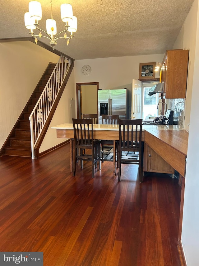 dining space with a chandelier, dark wood finished floors, a textured ceiling, and stairway