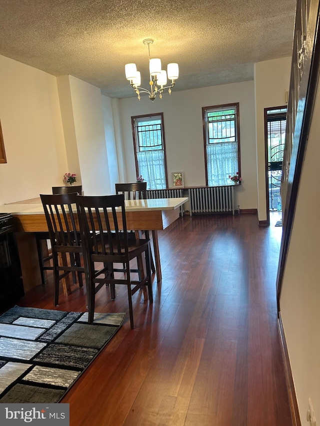 dining area featuring radiator heating unit, a chandelier, dark wood-type flooring, a textured ceiling, and baseboards