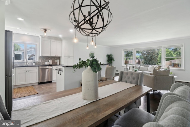 dining room with healthy amount of natural light, light wood-style floors, recessed lighting, and a chandelier