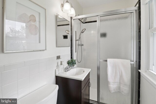 full bathroom featuring tile walls, a shower stall, vanity, and toilet