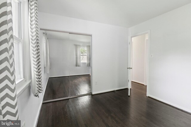 unfurnished bedroom featuring wood finished floors, a closet, and baseboards