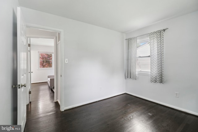 spare room with dark wood-type flooring and baseboards