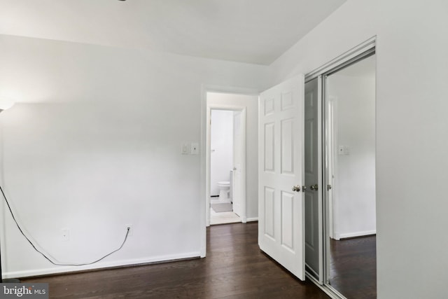 unfurnished bedroom with dark wood finished floors, a closet, and baseboards