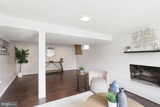 living room with wood finished floors, a fireplace, baseboards, and brick wall
