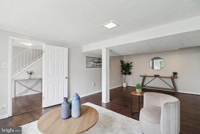 living area featuring wood finished floors, stairs, baseboards, and decorative columns