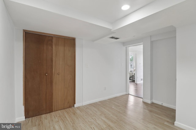unfurnished bedroom with light wood-type flooring, baseboards, and a closet