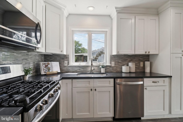 kitchen featuring appliances with stainless steel finishes, a sink, dark countertops, and backsplash