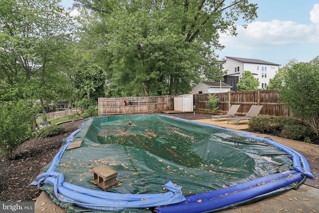 view of swimming pool featuring a fenced backyard, a storage unit, and an outdoor structure