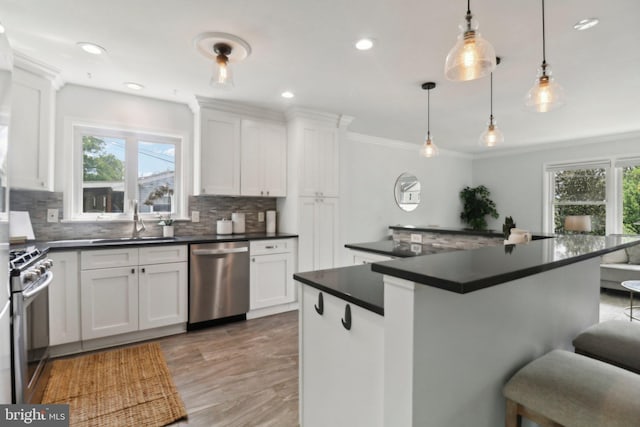 kitchen featuring stainless steel appliances, dark countertops, plenty of natural light, crown molding, and recessed lighting