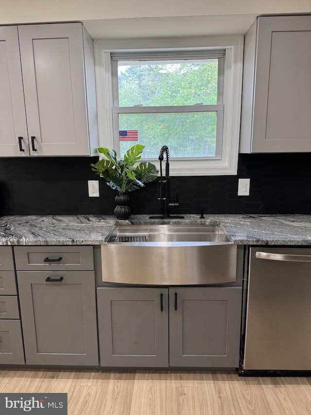 kitchen featuring dishwasher, gray cabinetry, a sink, and healthy amount of natural light