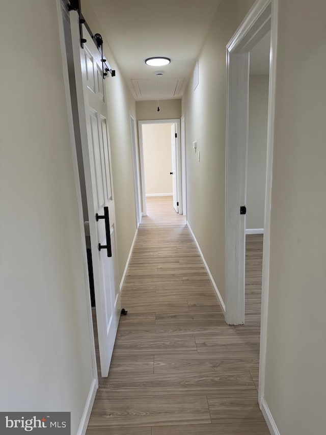 hall with attic access, wood finished floors, and baseboards