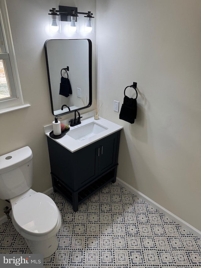 half bath featuring toilet, vanity, and baseboards