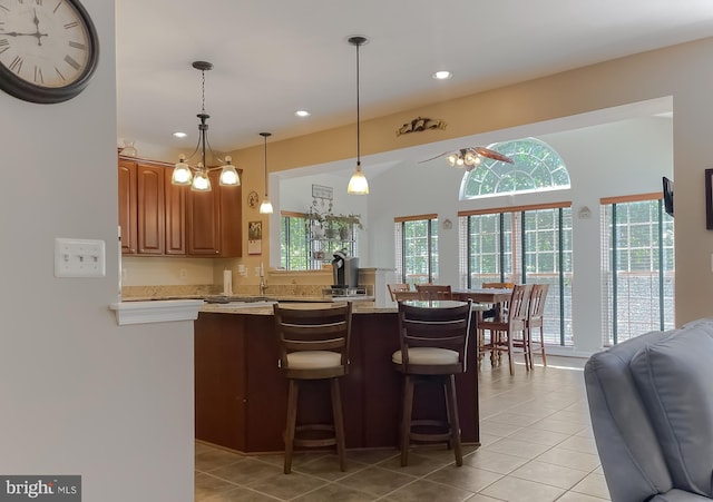 13605 Sugar Mill Ct, Waldorf, MD 20601 - kitchen featuring a breakfast bar area, a ceiling fan, light tile patterned flooring, recessed lighting, and brown cabinetry