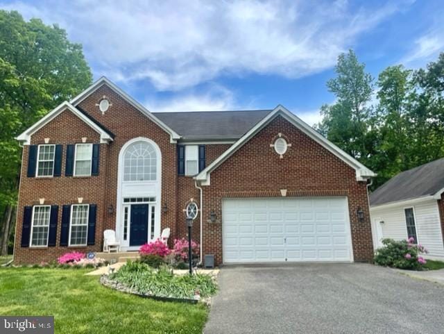 13605 Sugar Mill Ct, Waldorf, MD 20601 - colonial-style house featuring asphalt driveway, a garage, brick siding, and a front yard