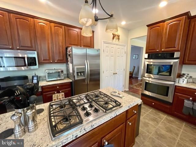 13605 Sugar Mill Ct, Waldorf, MD 20601 - kitchen featuring appliances with stainless steel finishes, light stone countertops, light tile patterned floors, and pendant lighting