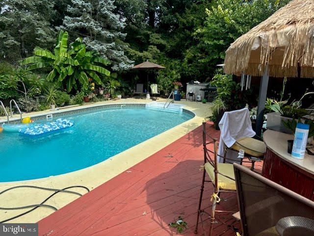swimming pool with a wooden deck and view of wooded area