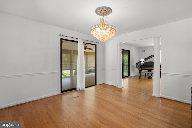 empty room with decorative columns, light wood finished floors, baseboards, and a ceiling fan