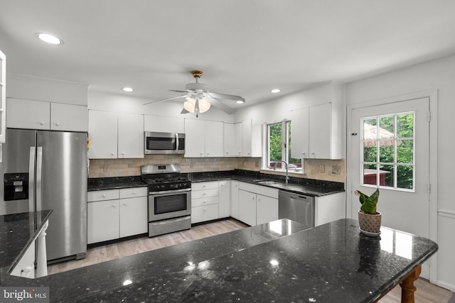 kitchen featuring appliances with stainless steel finishes, a sink, white cabinetry, backsplash, and recessed lighting