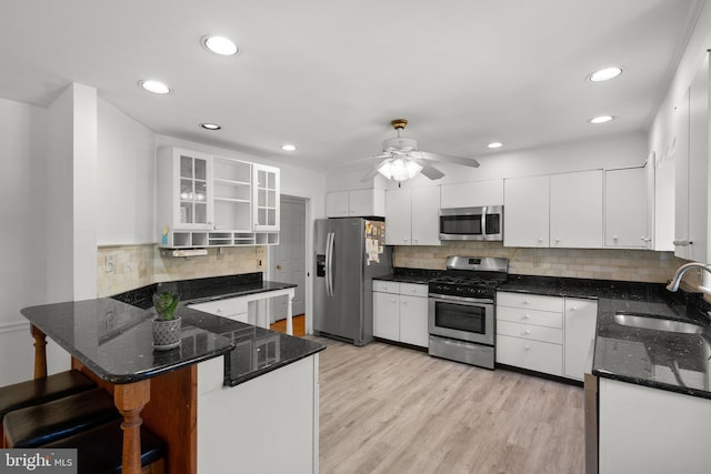 kitchen with appliances with stainless steel finishes, a sink, a peninsula, decorative backsplash, and ceiling fan