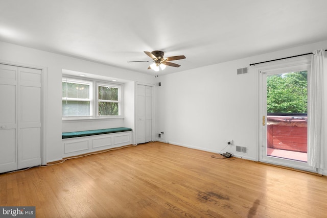 unfurnished bedroom featuring access to outside, light wood-style floors, multiple windows, and multiple closets