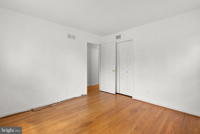 unfurnished bedroom featuring light wood-style floors, baseboards, and a closet