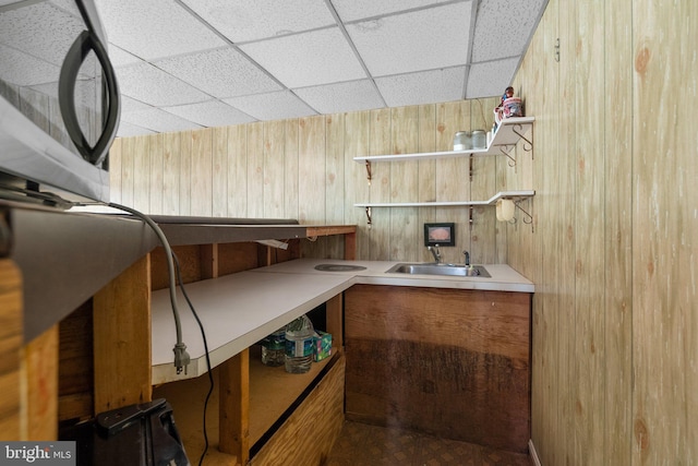 miscellaneous room with wood walls, a paneled ceiling, and a sink