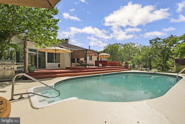 swimming pool with a patio, a wooden deck, and a grill