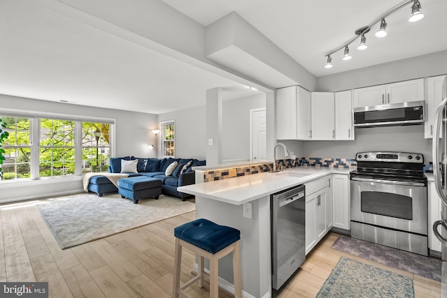 2224 Springwood Dr Unit 102A, Reston, VA 20191 - kitchen featuring appliances with stainless steel finishes, a sink, open floor plan, a peninsula, and white cabinetry
