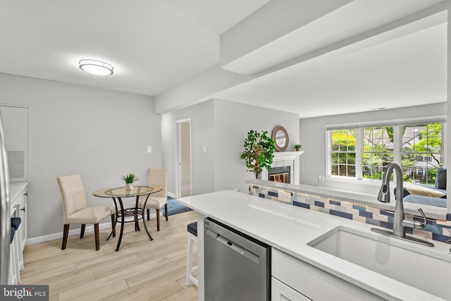 2224 Springwood Dr Unit 102A, Reston, VA 20191 - kitchen featuring dishwasher, a sink, light wood-type flooring, white cabinets, and a tile fireplace