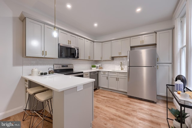 kitchen with stainless steel appliances, a sink, a peninsula, tasteful backsplash, and recessed lighting