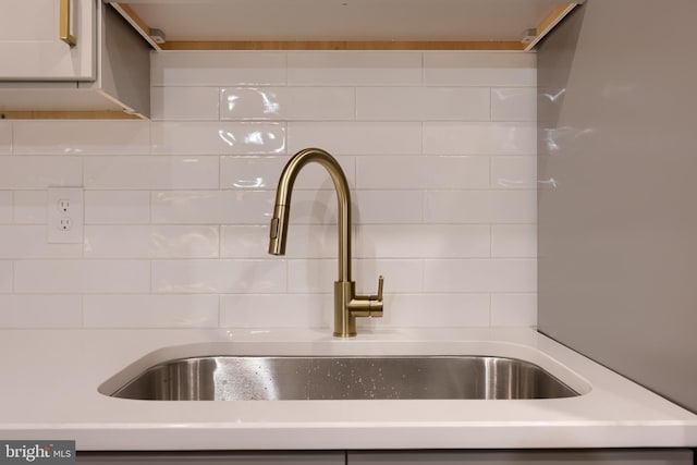 kitchen view of a sink, decorative backsplash, and light countertops