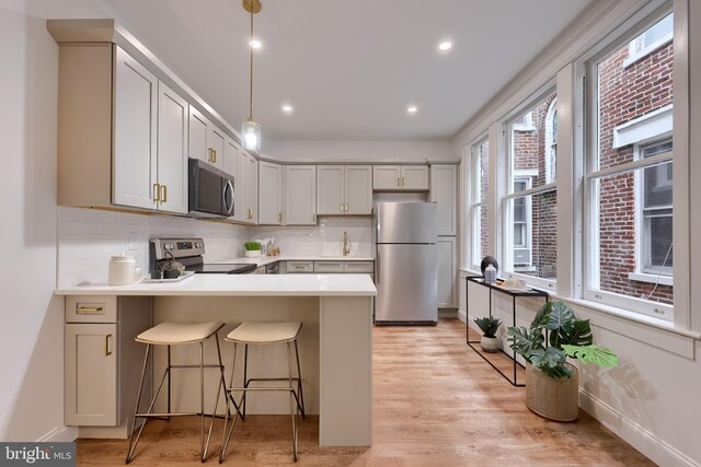 kitchen featuring stainless steel appliances, a peninsula, backsplash, light countertops, and recessed lighting