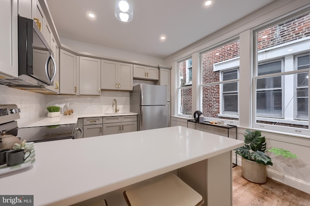 kitchen featuring appliances with stainless steel finishes, gray cabinets, a peninsula, light countertops, and recessed lighting