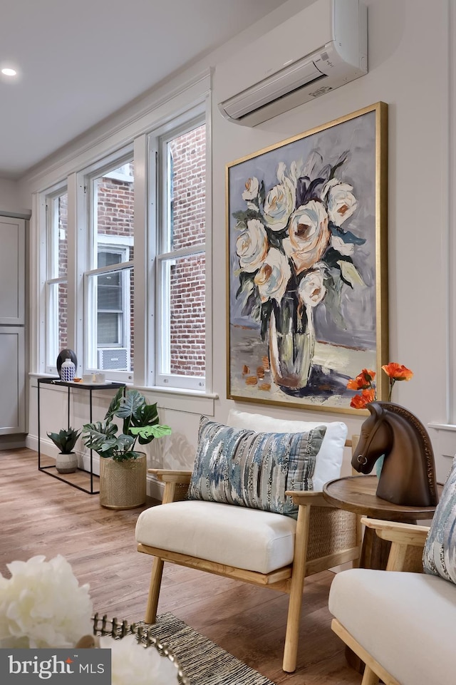 sitting room with a wall mounted air conditioner, light wood-style floors, healthy amount of natural light, and recessed lighting