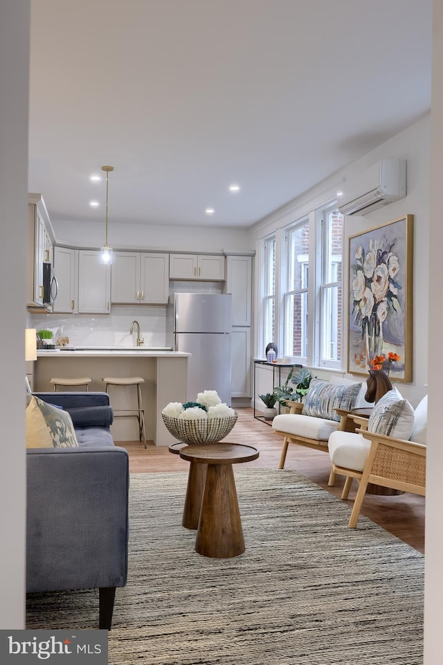 living area featuring a wall mounted air conditioner, light wood-type flooring, and recessed lighting