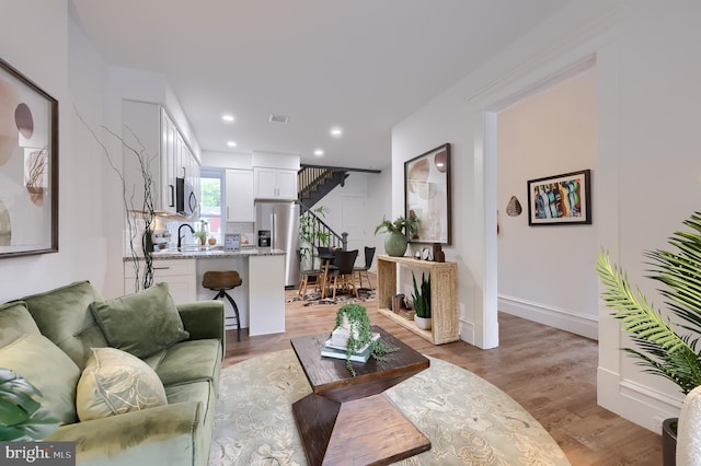 living room featuring light wood-style flooring, recessed lighting, and baseboards