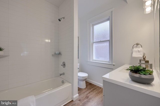 full bath featuring toilet, wood finished floors, vanity, baseboards, and shower / washtub combination