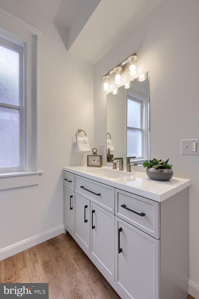 bathroom with vanity, wood finished floors, and baseboards