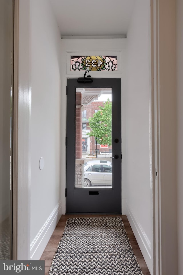 doorway to outside with wood finished floors and baseboards