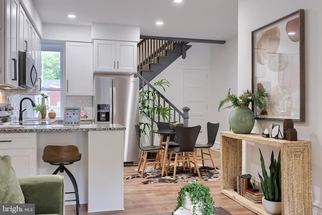 kitchen featuring appliances with stainless steel finishes, white cabinetry, light stone countertops, tasteful backsplash, and recessed lighting