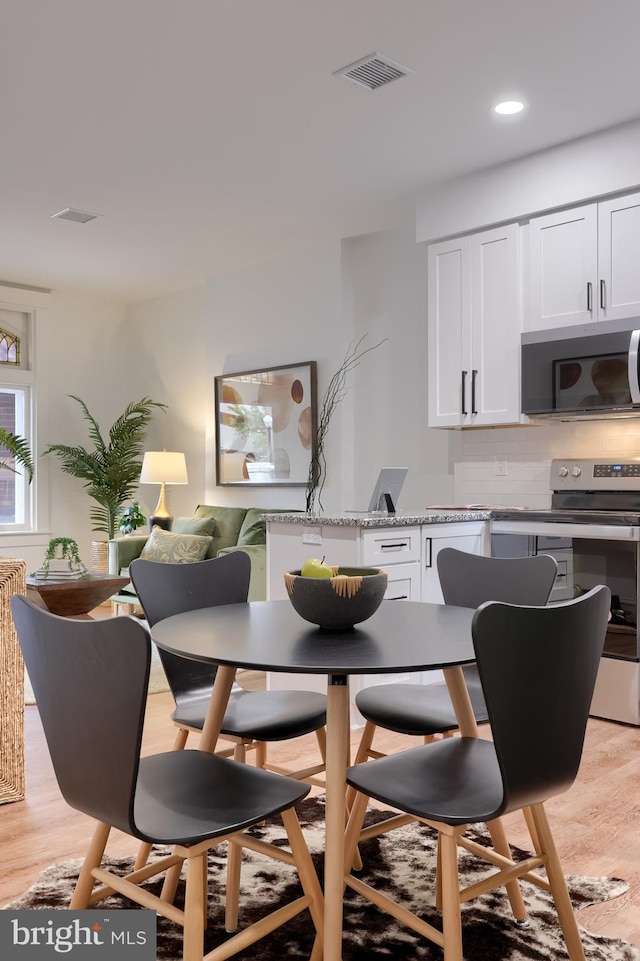 dining space with light wood-type flooring and recessed lighting