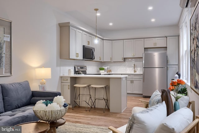 kitchen featuring appliances with stainless steel finishes, open floor plan, a peninsula, a breakfast bar area, and backsplash