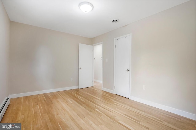 unfurnished room with light wood-style flooring, a baseboard radiator, and baseboards