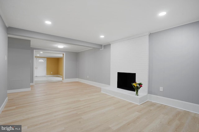 unfurnished living room featuring light wood-type flooring, baseboards, a fireplace, and recessed lighting