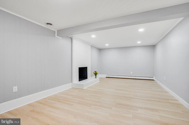 below grade area featuring a baseboard heating unit, wood finished floors, a brick fireplace, recessed lighting, and baseboards