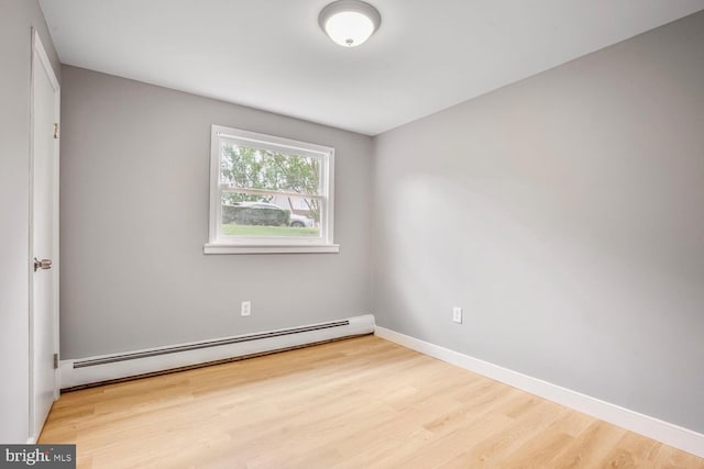 unfurnished room with a baseboard radiator, wood finished floors, and baseboards