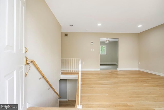 stairs featuring wood finished floors, a baseboard radiator, baseboards, and recessed lighting