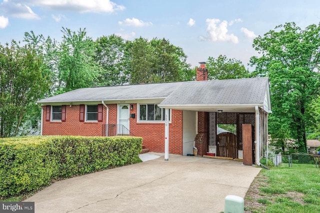 ranch-style house featuring concrete driveway, a chimney, fence, brick siding, and a carport