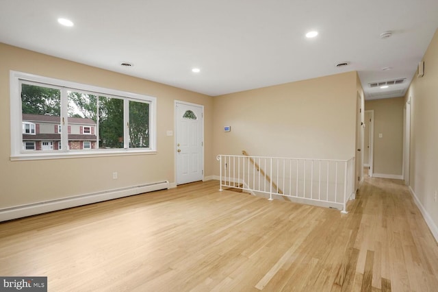 empty room with baseboard heating, light wood-style floors, a smoke detector, baseboards, and recessed lighting