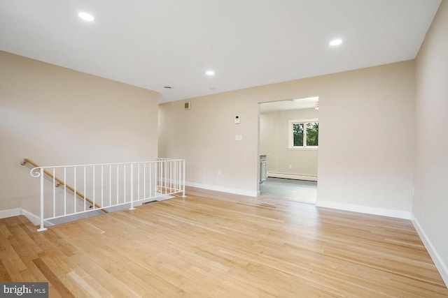 empty room featuring baseboard heating, light wood-style floors, baseboards, and recessed lighting